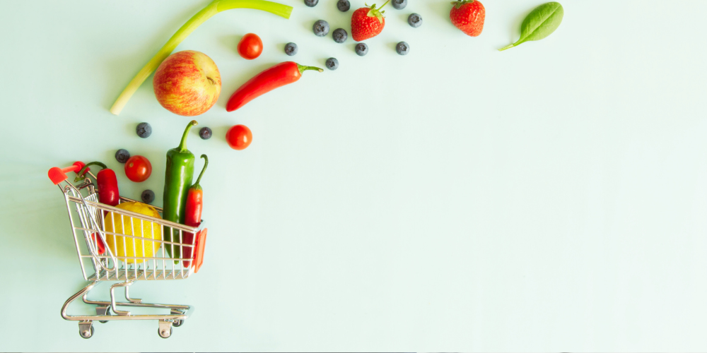 A miniature shopping trolley with fruit and vegetables floating away from it